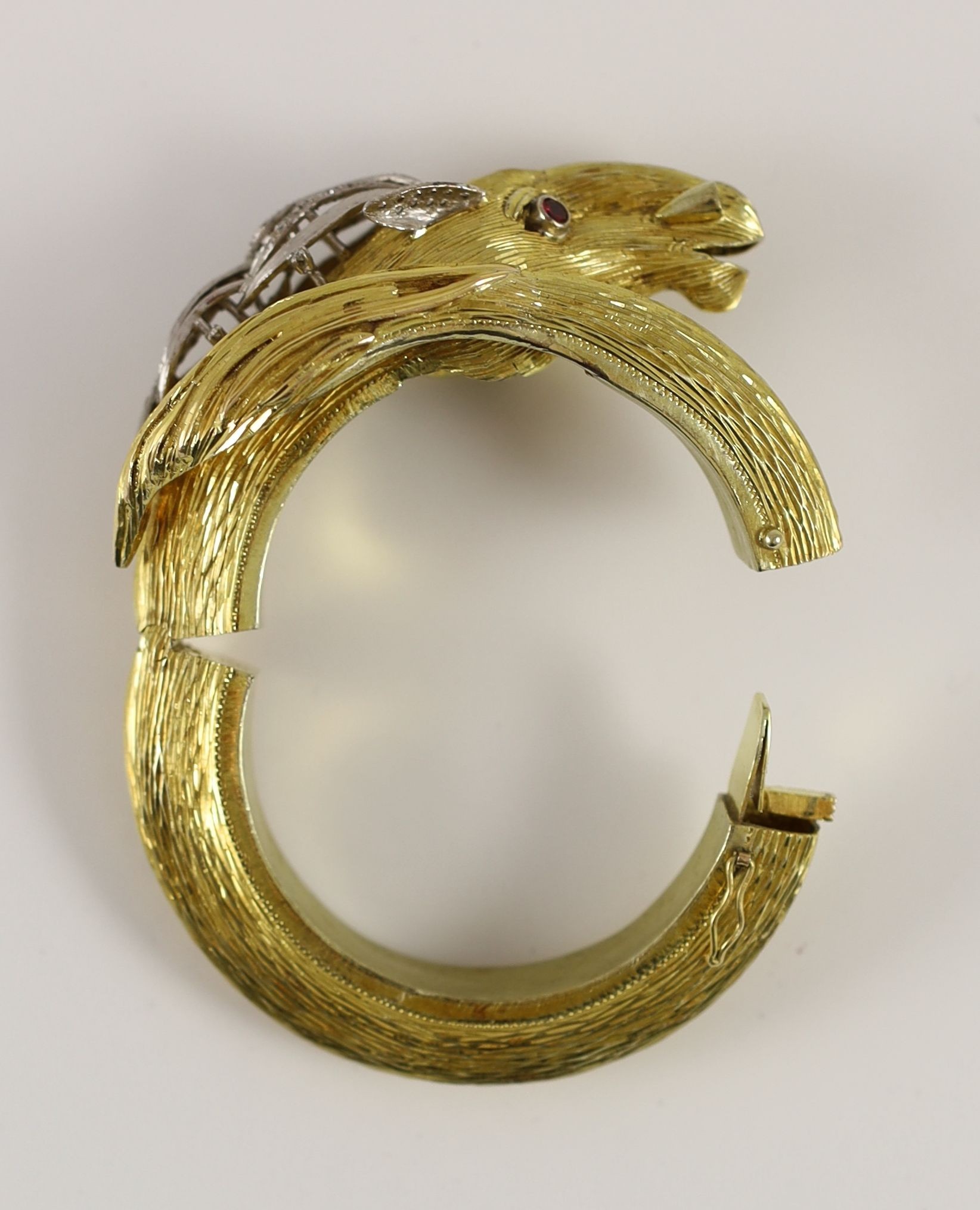 A 20th century Continental textured 14k gold, ruby and diamond set hinged bangle, modelled as the head and tail of a horse